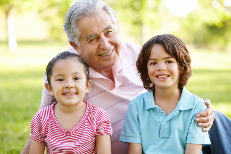 Hispanic Grandmother And Grandfather Relaxing With Grandson In Park